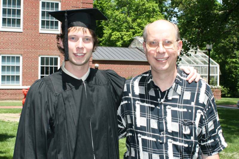 a man in a graduation cap and gown standing next to a man in a black and white robe