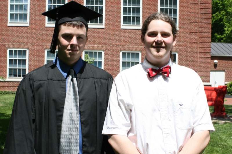 a man in a graduation gown and cap standing next to a man in a tie