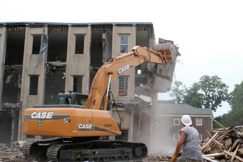 a construction worker using a bulldozer to demolish a building