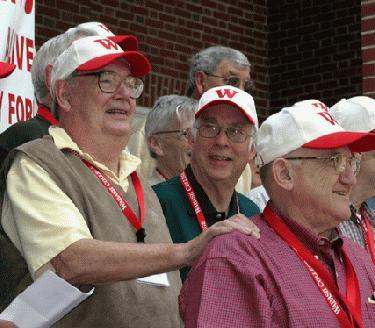 a group of older men wearing red and white hats
