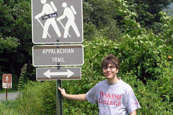 a young man standing next to a sign