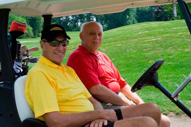 two men sitting in a golf cart