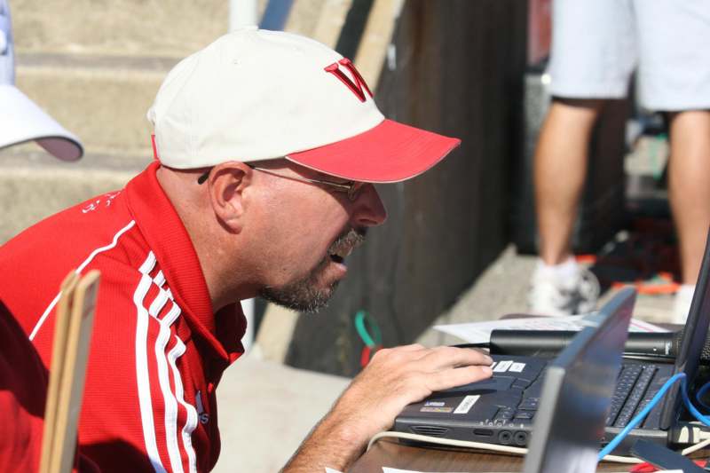 a man in a red shirt and white hat using a laptop