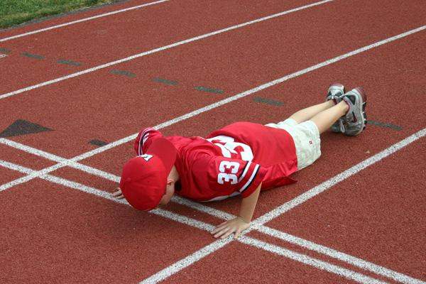 a boy doing push ups on a track