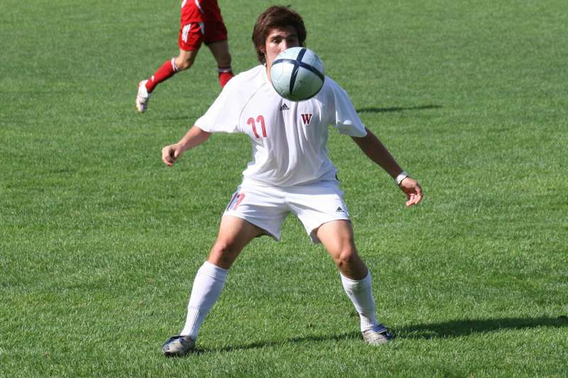 a man in a white uniform kicking a football ball