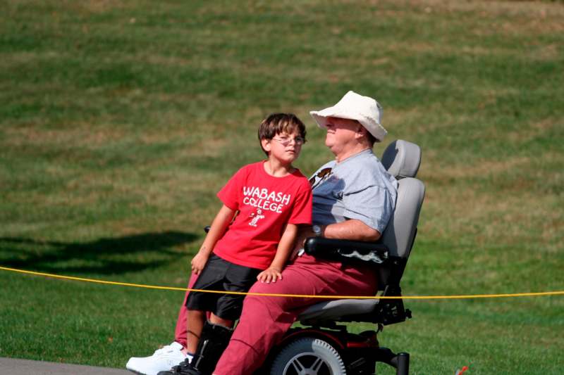 a man in a wheelchair with a boy in a red shirt