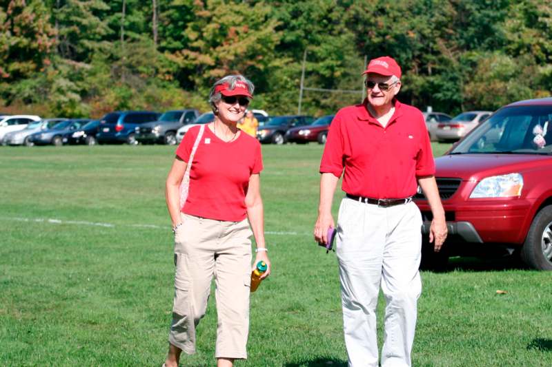 a man and woman in red shirts and hats walking on a field
