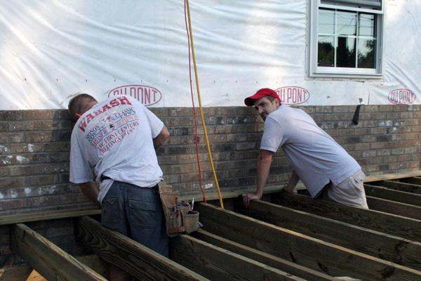 a few men working on a wood beam