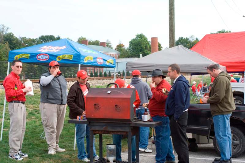 a group of men standing around a barbecue grill