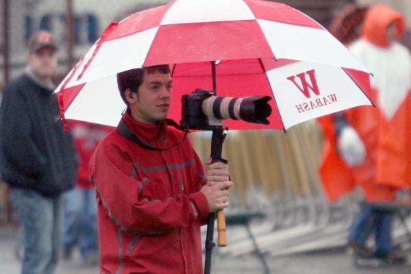 a man holding a camera under an umbrella