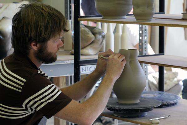 a man painting a vase on a pottery wheel