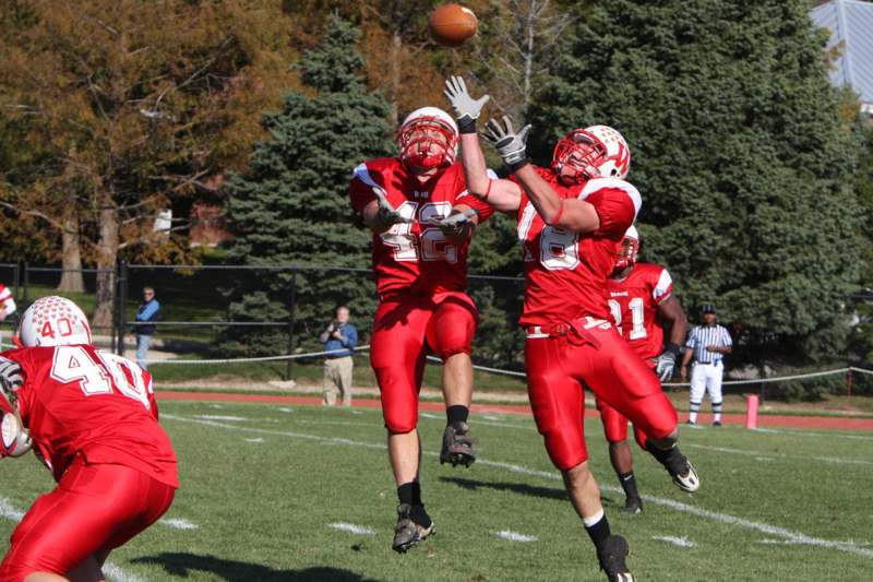 a football players in red uniforms jumping to catch a football