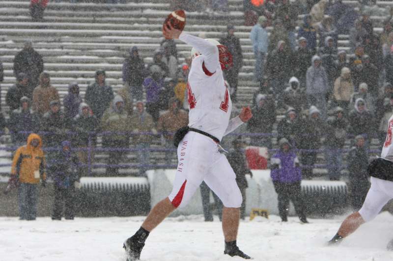 a football player throwing a football in the snow