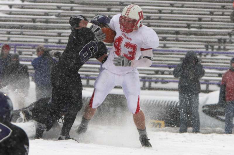 a football player in a white uniform running with a football in the snow