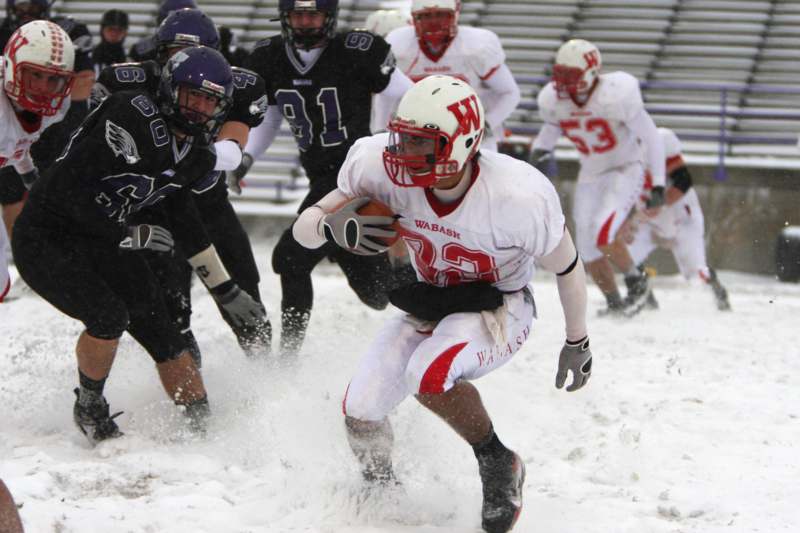 a football player running with the ball in the snow