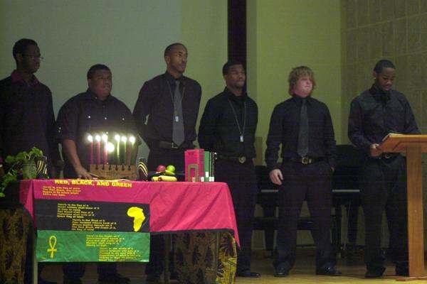 a group of men standing in front of a table with candles