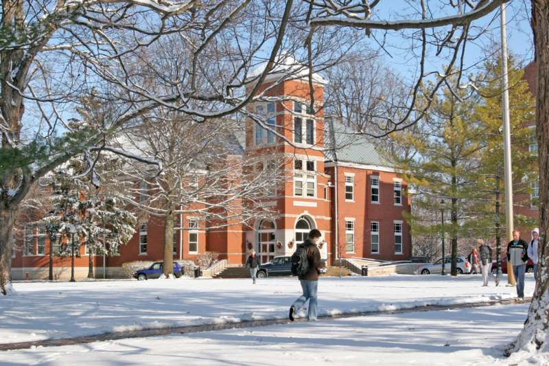 a man walking in the snow with Wabash College in the background