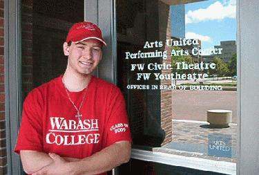 a man in red shirt standing in front of a window