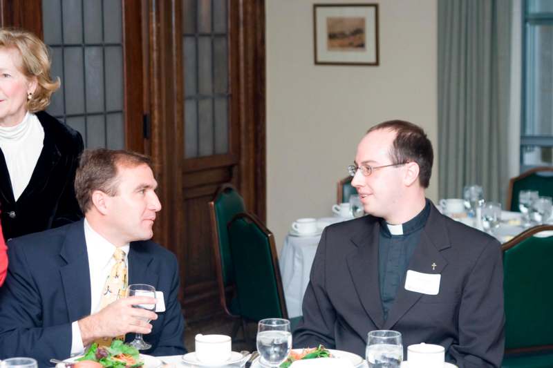 a man and a priest talking at a table
