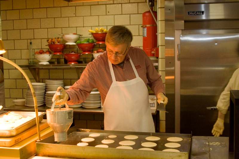 a man in a kitchen making pancakes