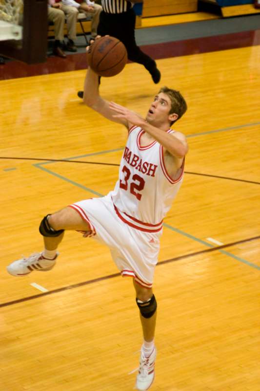 a man in a basketball uniform jumping to shoot a basketball
