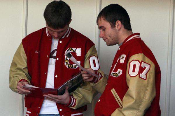 a couple of men in red jackets looking at a book