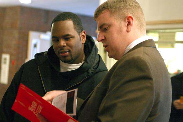 medium shot of men looking at a red folder