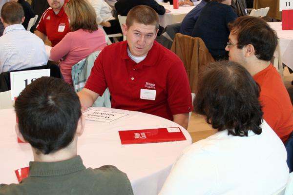 a man sitting at a round table with people in the background