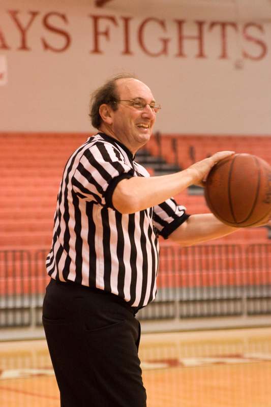 a man in a black and white striped shirt holding a basketball