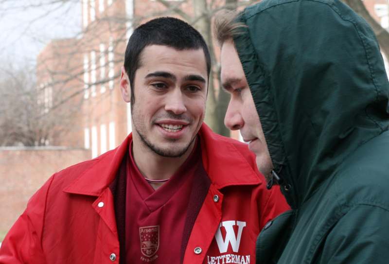 a man in a red jacket talking to another man