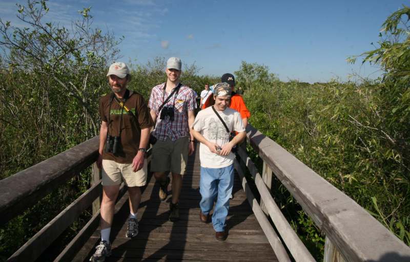 a group of people walking on a wooden bridge