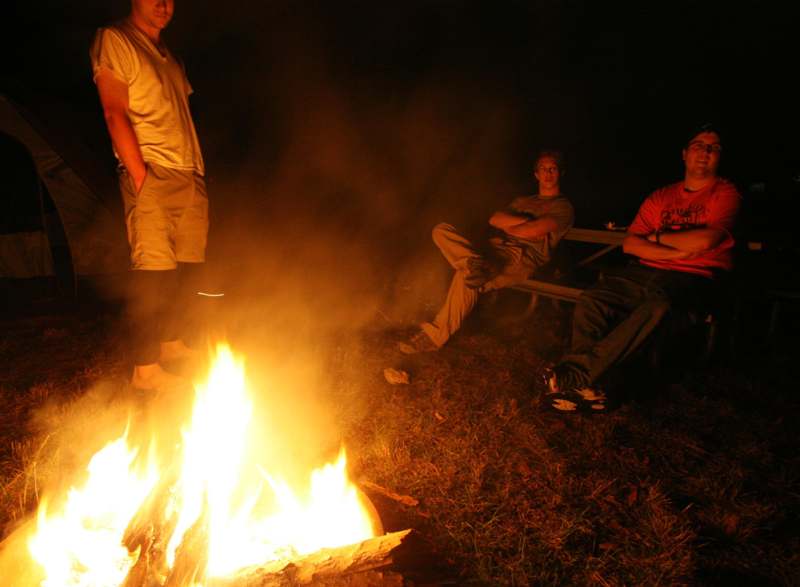 a group of men sitting around a fire
