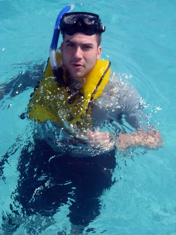a man wearing a life vest and goggles swimming in a pool