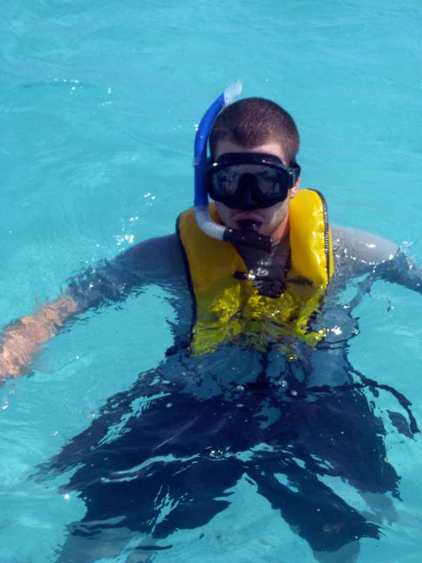a man wearing a life jacket and goggles swimming in the water