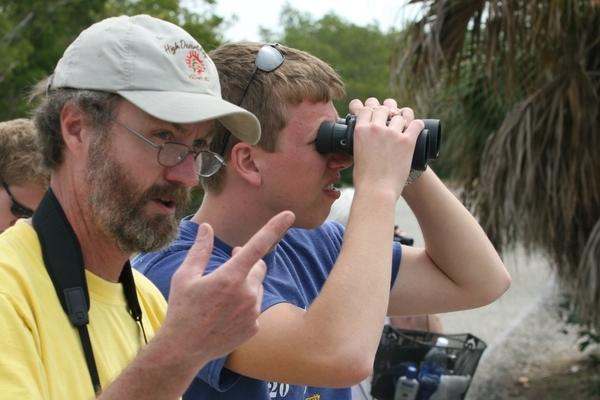 a man holding binoculars and another man pointing at him