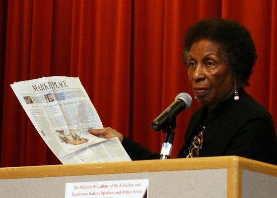 a woman reading a newspaper at a podium