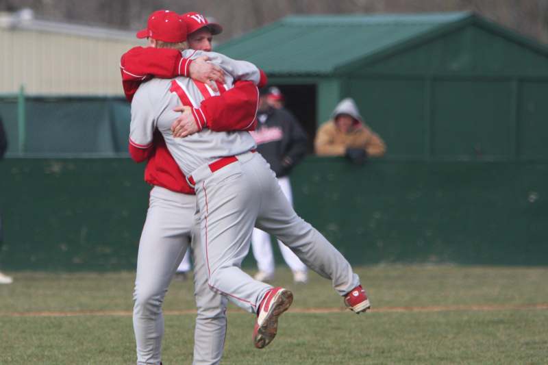 two baseball players hugging on a field