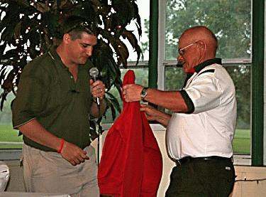 a man holding a microphone and another man holding a red jacket