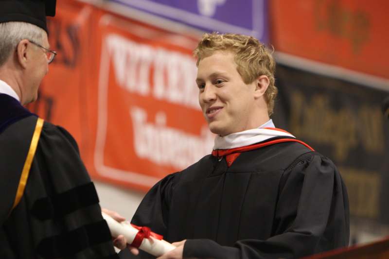 a man in a black robe holding a diploma