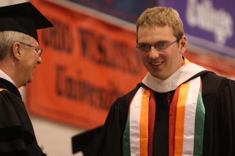 a man wearing a graduation gown and glasses