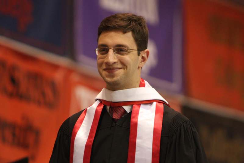 a man wearing a graduation gown and a red and white scarf