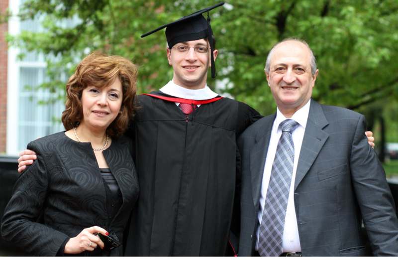 a man and woman standing together with a man in a graduation gown