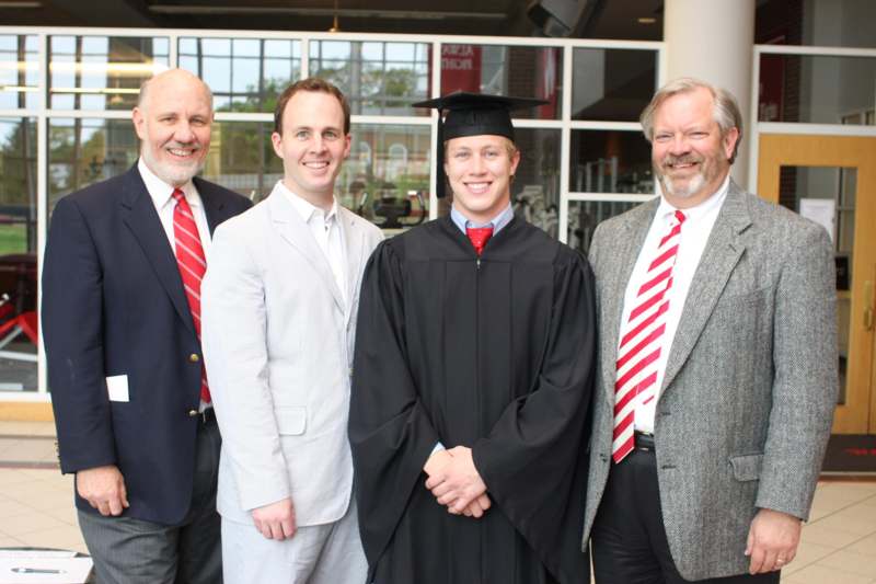 a group of men in suits and a graduation gown