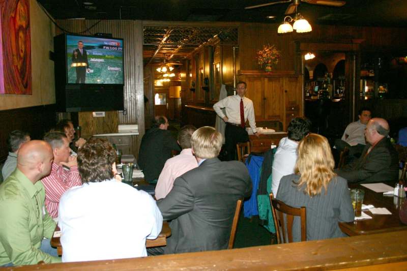 a man standing in front of a group of people seated in a restaurant