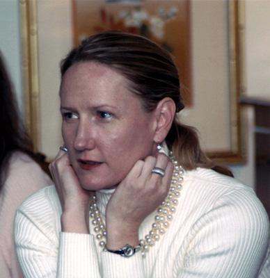 a woman wearing a white sweater and a pearl necklace