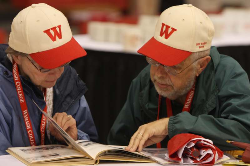 a man and woman wearing hats looking at a book