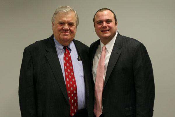 a man in a suit and tie standing next to another man in a suit and tie