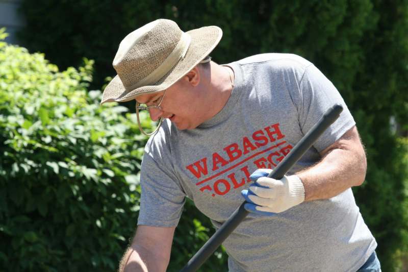 a man wearing a hat and gloves holding a shovel
