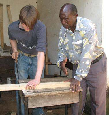 a man and a young man cutting a piece of wood