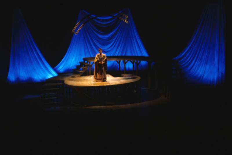 a man on a stage with blue curtains